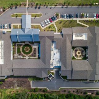 Aerial view of a building complex with parking lots and landscaped gardens.