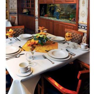 An elegantly set dining table with fine china, cutlery, and floral centerpieces in a cozy restaurant setting.