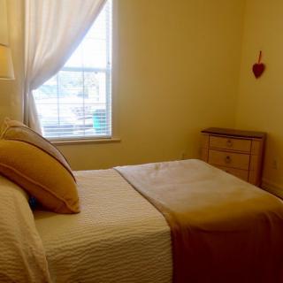 A cozy bedroom with a neatly made bed, soft lighting, and a window with curtains.