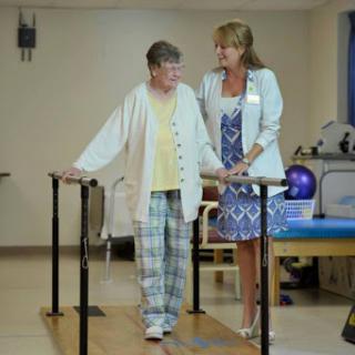 A physical therapist assists an elderly patient in walking during a rehabilitation session.
