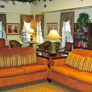 A cozy living room with orange sofas, stylish lamps, and a bookshelf.
