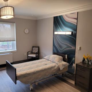 A modern hospital room featuring a bed, bedside table, and soothing wall design.