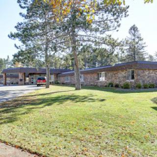 A peaceful residential building surrounded by green grass and trees.