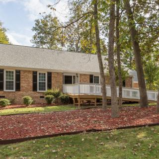 A brick ranch-style house surrounded by trees and landscaped front yard.