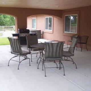 A covered patio area with a table and chairs set, featuring large windows and an outdoor view.