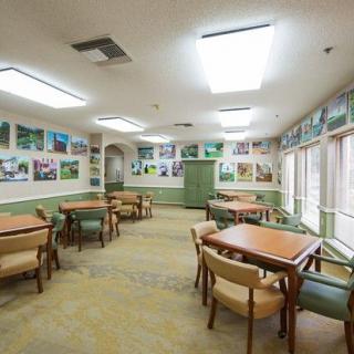 A well-lit dining area with tables and chairs, decorated with various artworks on the walls.