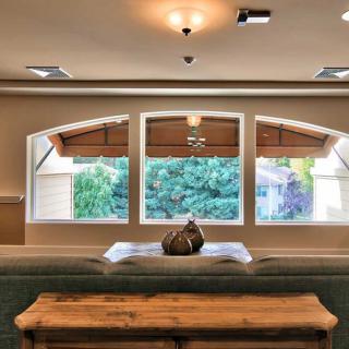A cozy living room with large windows and a wooden table.