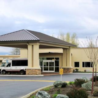 A hotel's main entrance with a covered driveway and shuttle bus parked outside.
