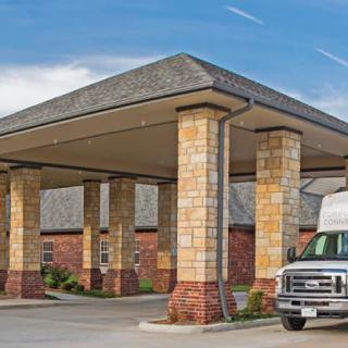 A building entrance with a covered driveway and a parked van nearby.