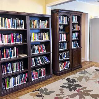 A warm and inviting space featuring two wooden bookshelves filled with various books, complemented by a decorative area rug.