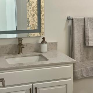 A modern bathroom with a marble countertop, mirror, and neatly hung towels.