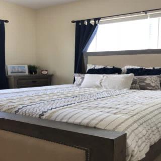 A neatly arranged bedroom with a large bed, striped bedding, and dark curtains.