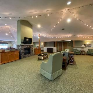 A spacious lounge with comfortable seating, a fireplace, and ambient string lighting.