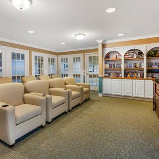 A cozy home theater with comfortable armchairs and built-in bookshelves.