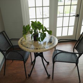 A cozy indoor seating area featuring a round table with potted plants and two metal chairs.