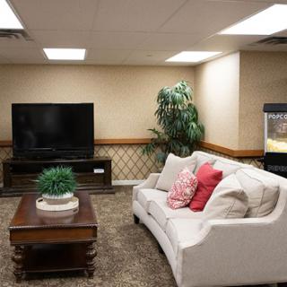 A cozy living room with a white sofa, a coffee table, and a large television.