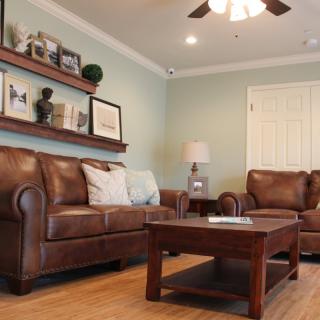 A cozy living room with leather sofas, a wooden coffee table, and decorative shelves.