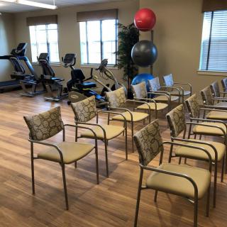 A gym with fitness equipment and a meeting space with chairs and exercise balls.
