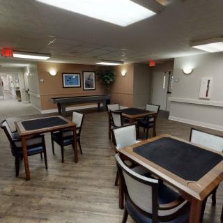 A modern dining area with neatly arranged tables and chairs, featuring a wooden floor and contemporary lighting.
