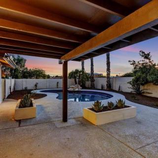 A serene backyard patio with a swimming pool and planters, framed by palm trees under a sunset sky.