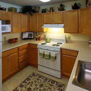 A cozy kitchen with wooden cabinets, a stove, and a sink.