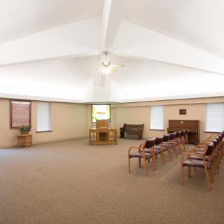 A spacious and well-lit interior with chairs arranged in rows, suitable for gatherings or meetings.
