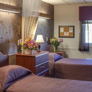 A cozy and well-decorated bedroom with two beds, warm lighting, and fresh flowers.