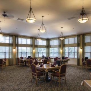 A spacious dining room with large windows and arranged tables and chairs.