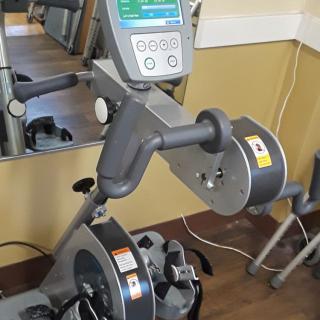 A gym cardio machine, designed for upper body workouts, displayed in a fitness center.