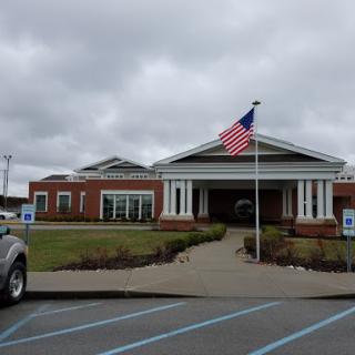 A view of a well-structured building featuring an American flag in front, set against a cloudy sky.