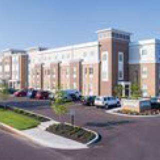 A modern hotel building with a brick exterior, surrounded by a parking lot and landscaped grounds.