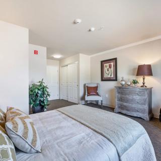 A cozy bedroom with stylish decor, featuring a bed, dresser, and accent chair.