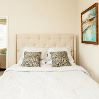 A neatly made bed with patterned pillows and a framed artwork on the wall in a cozy bedroom.