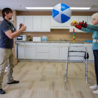 A person and a therapist engaging in an interactive ball-throwing activity to enhance rehabilitation skills.