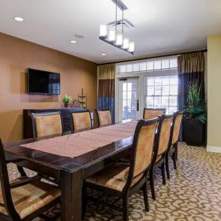 A well-furnished dining or conference room featuring a long table surrounded by chairs, with modern lighting and decor.