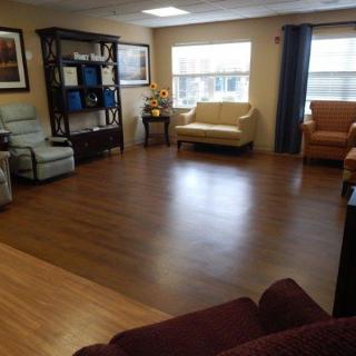 A cozy living room with hardwood flooring and multiple seating options.