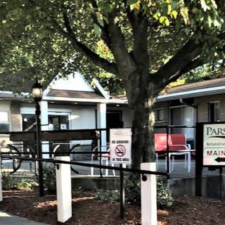 A small building with a ramp, surrounded by trees and signage.