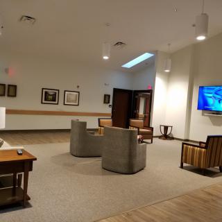 A modern lobby area with comfortable seating, artwork on the walls, and a television.