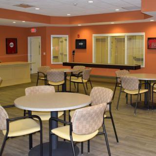 A community seating area with tables and chairs in a warmly decorated room.