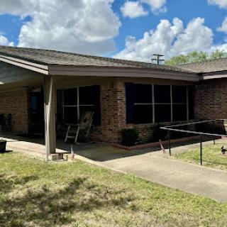 A charming residential home with a well-maintained lawn and clear blue skies.