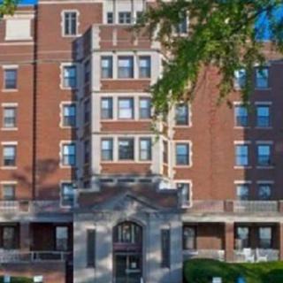 A multi-story brick residential building with numerous windows and a central entrance.