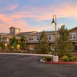 A residential building with trees and a parking lot under a colorful sunset sky.