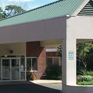 A modern building entrance with a green roof and glass doors.