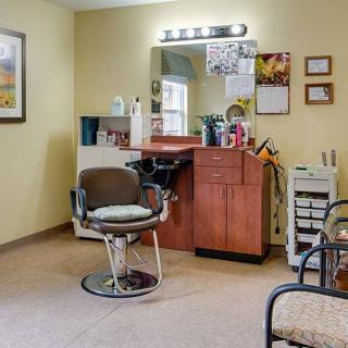 A cozy salon interior with a styling chair, mirror, and beauty station.