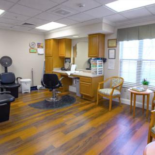 A hair salon interior with styling chairs, a mirror, and a small waiting area.