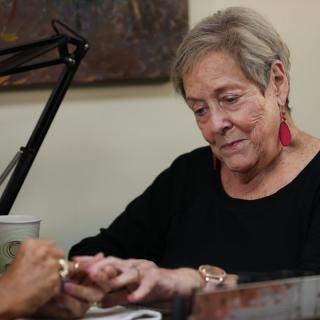 An elderly woman is focused on reading something indoors.