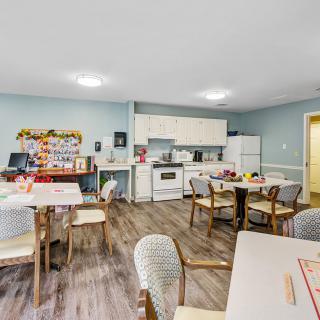 A community kitchen and dining area with tables, chairs, and cooking appliances.