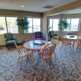 A cozy lounge area with tables, chairs, and large windows letting in natural light.