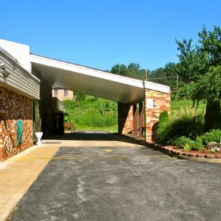 A building with a covered driveway surrounded by greenery on a sunny day.