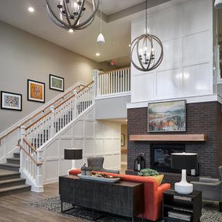 A modern living room with a stylish staircase, elegant chandeliers, and contemporary artwork.